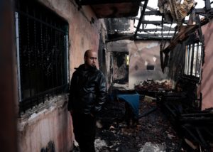 A man inspects a damaged house, which Palestinians say was burned by Israeli settlers last night, in Al-Fandaqumiya