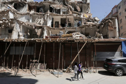 People walk in front of a damaged building in the southern suburbs of Beirut