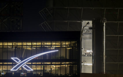 SpaceX Super Heavy booster rolls past the production facility toward launch pad 2, in Starbase, Texas