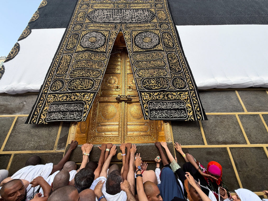Muslim pilgrims reach out to touch the Kaaba's door at the Grand Mosque, ahead of the annual hajj pilgrimage, in Mecca