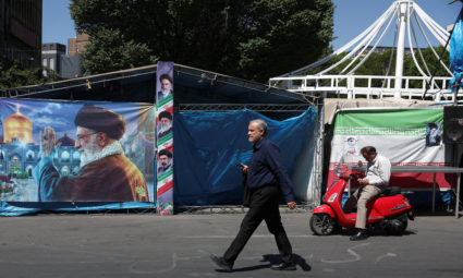 A man walks past a banner with a picture of Iran's late Supreme Leader Ayatollah Ali Khamenei, in Tehran