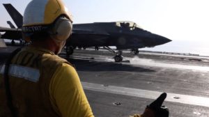 still image released by U.S. Central Command (CENTCOM) shows shows a flight deck crew member signaling an F‑35 jet on an a...