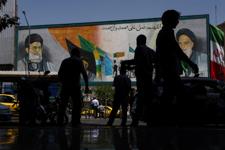 People walk past a mural depicting late Iranian leaders in Tehran