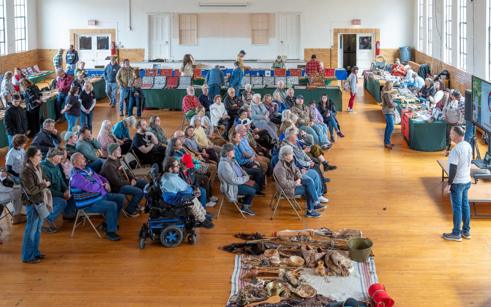 Dozens of people, seated in multiple rows of chairs, gather for a presentation during Talbot County's Native American Heritage and Artifact Day, held in February. Some Native Americans artifacts are seen on the floor, near the small crowd.