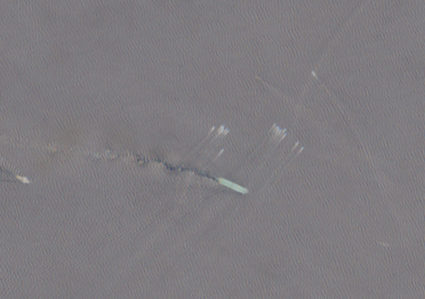 A satellite image shows a group of small boats near the Strait of Hormuz