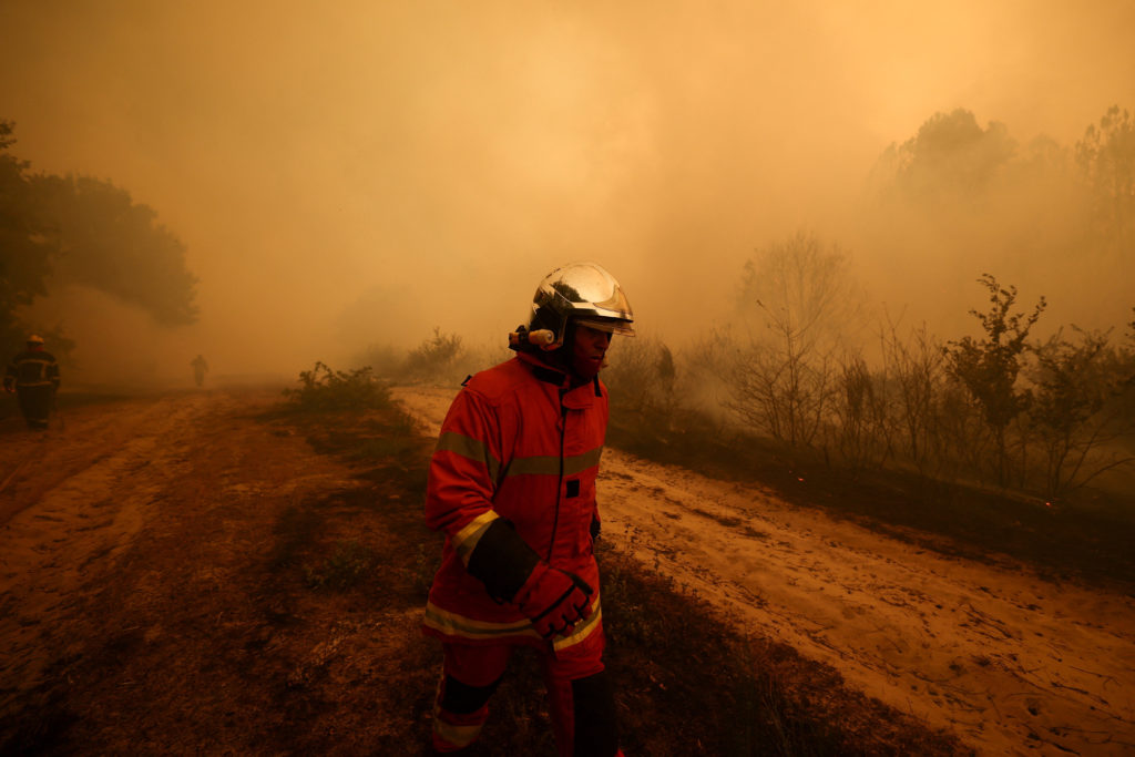 Tens of thousands of people flee raging wildfires in France and Spain, some escaping by boat