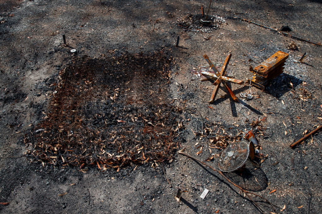 The remains of a mattress, a bedside table, a ventilator and a radiator are scattered on the scorched ground at the Kangar...