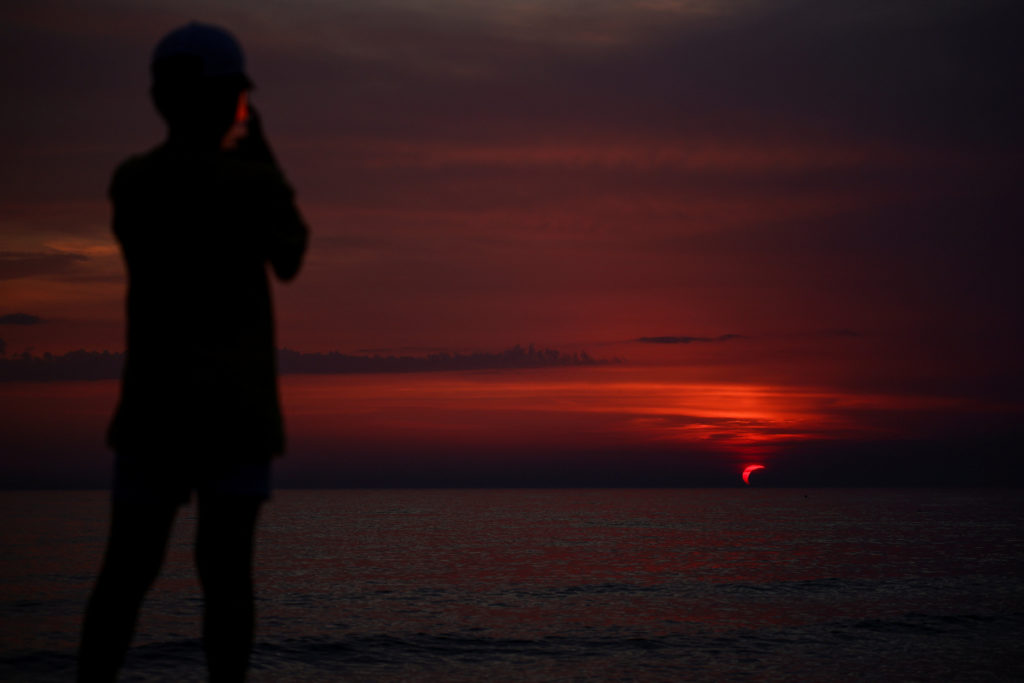 Partial solar eclipse draws eyes skyward on Italian beach