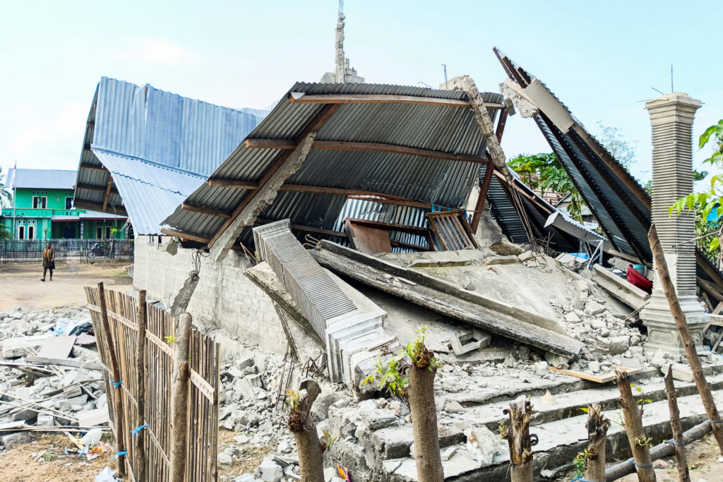 A person walks near a heavily-damaged house after an earthquake felt in Nanga Mbaur Village, East Manggarai, East Nusa Ten...