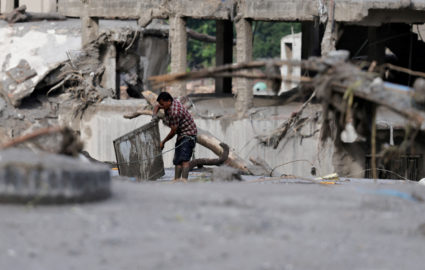 A man salvages his belongings from mud following devastating floods, in Trishuli
