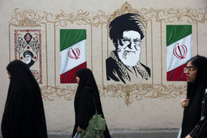 People walk by a mural depicting Iran's late Supreme Leader Ayatollah Ali Khamenei in Tehran